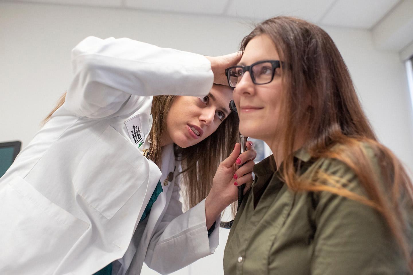 Osteopathic medical student looks in a patient's ear